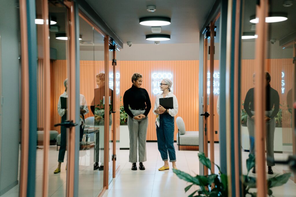 DEI backlash and the UK response. This image shows two female employees standing and talking in a work environment